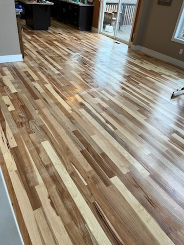 Glossy refinished floor reflecting light near a kitchen